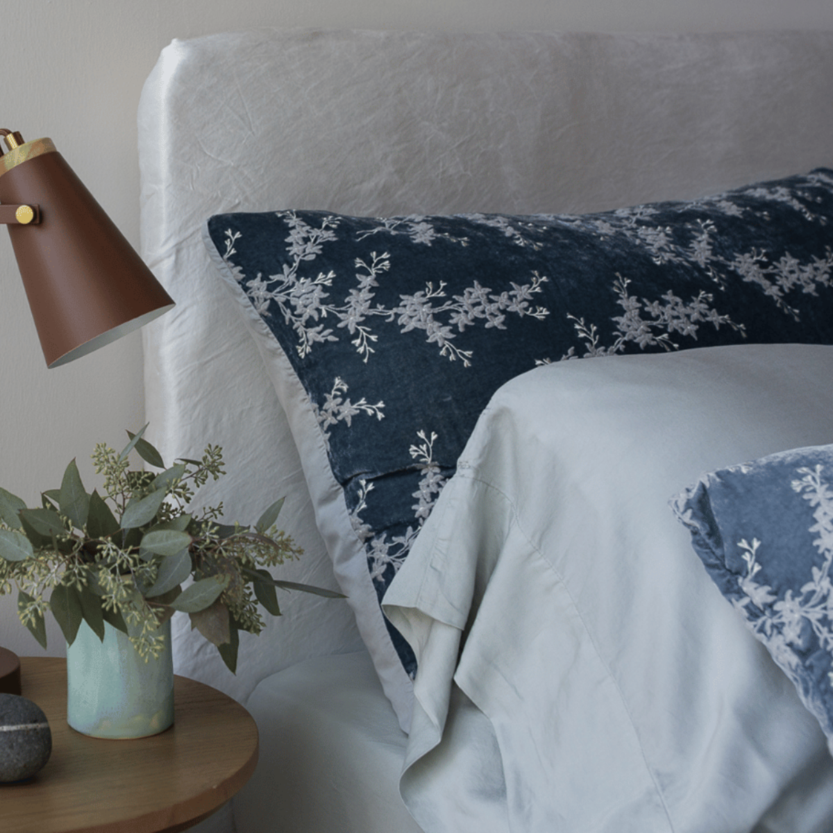 : a blue-grey sham shown with tencel pillowcase against a charmeuse fabric covered headboard. 