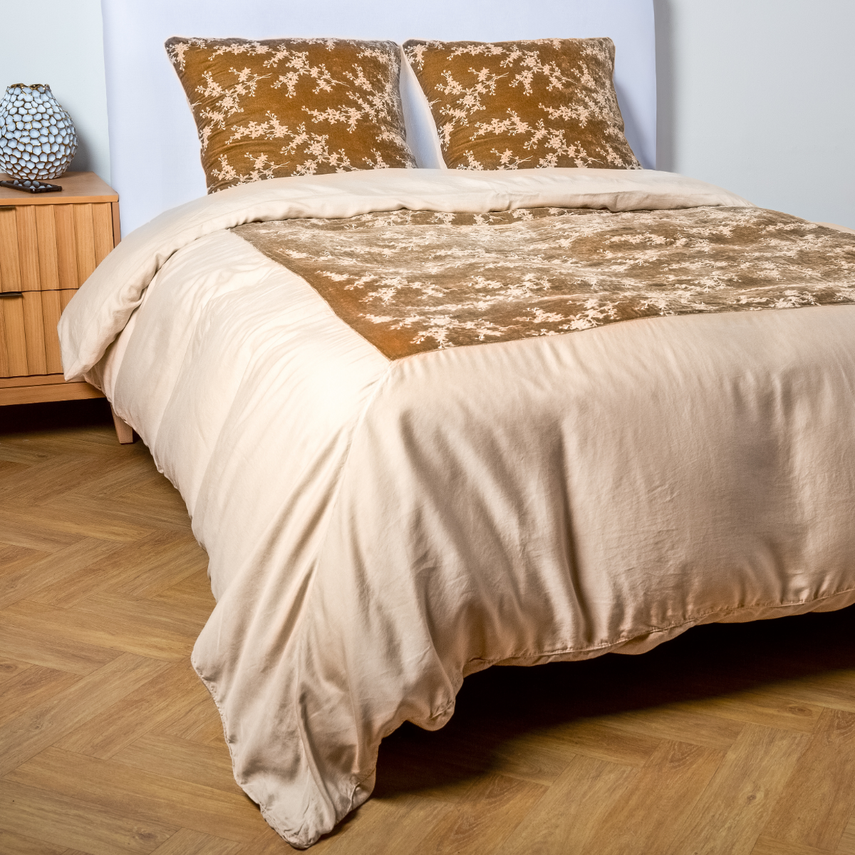 Honeycomb: A ¾ angle shot of an embroidered silk velvet and tencel duvet cover and matching shams with a vase and cell phone on the side table. 