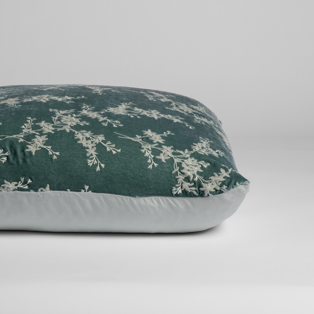 Eucalyptus: A close-up of the sham shown on its side to display the embroidered silk velvet face and tencel back — shown against a white background. 