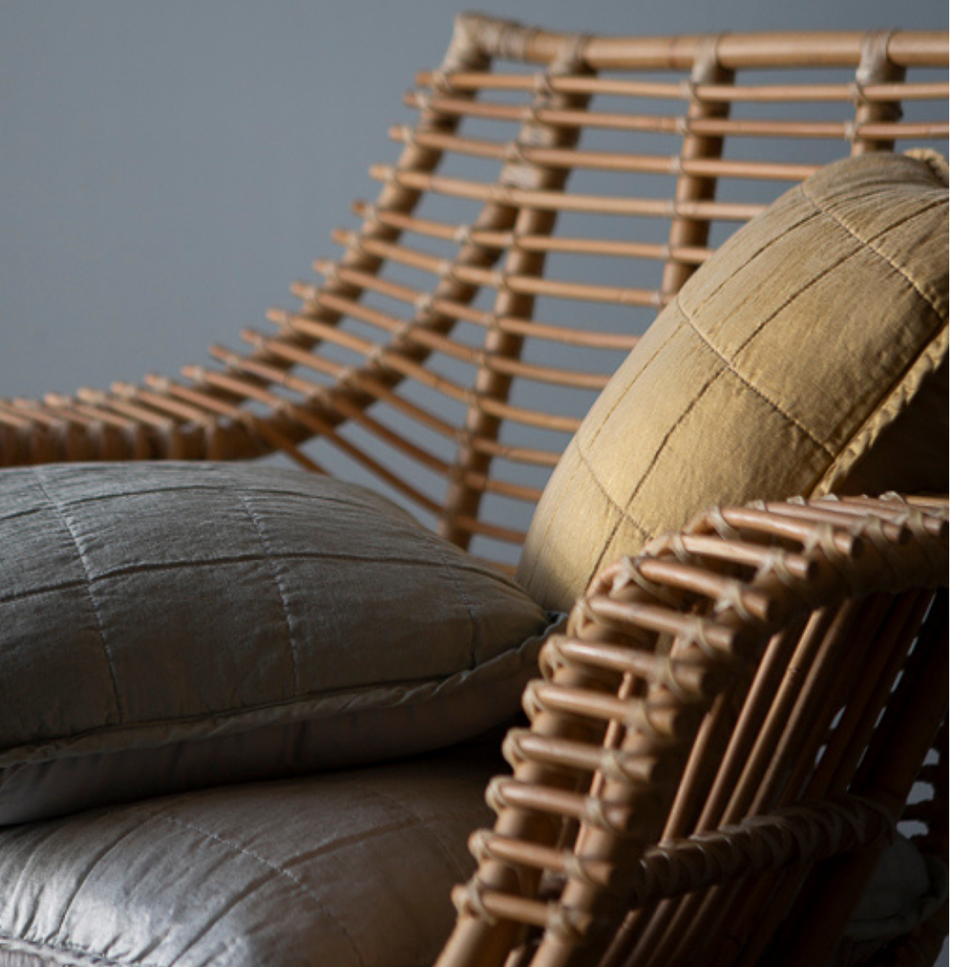 : a close up of quilted charmeuse throw pillows in a rattan chair.