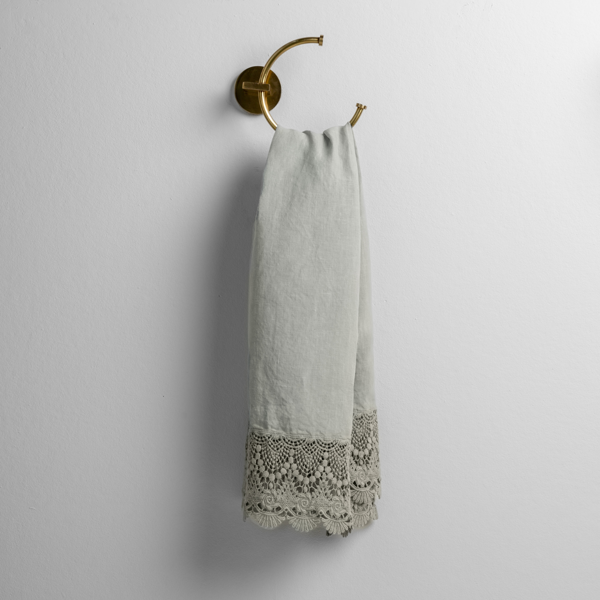 Eucalyptus: linen with mattine lace trimmed guest towel on a decorative towel ring mounted on a white wall. 