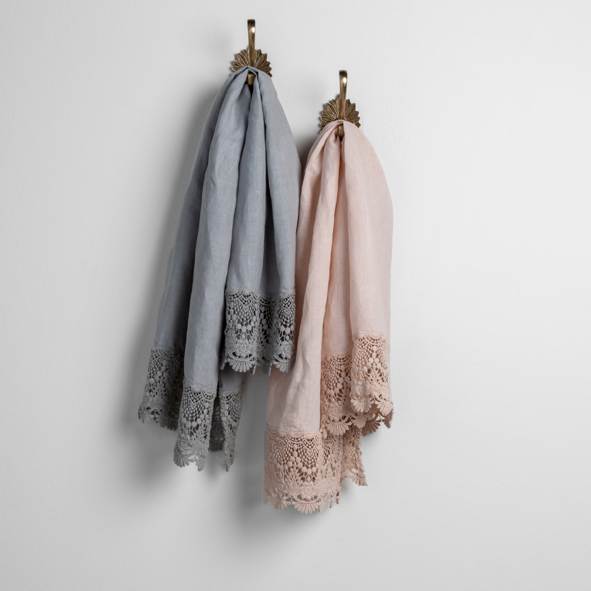 [allvariants]: pair of linen guest towels with mattine lace hanging from decorative towel hooks against a white wall - mineral and pearl.