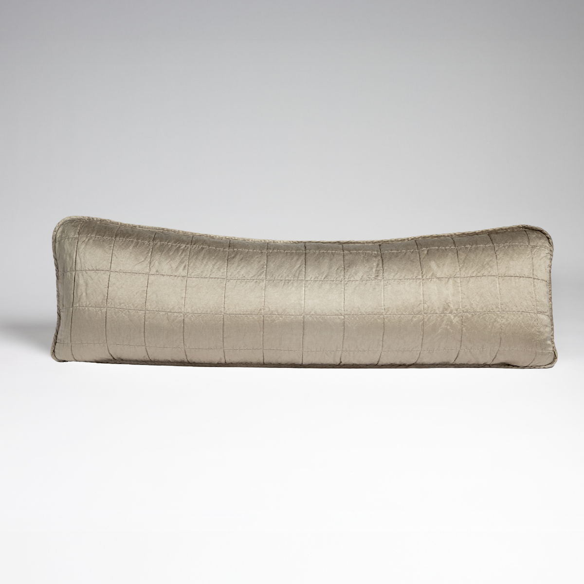Moonlight: A straight-on shot of a square-quilted body pillow in moonlight, a saturated, cool, mid-dark grey tone, against a white background. 