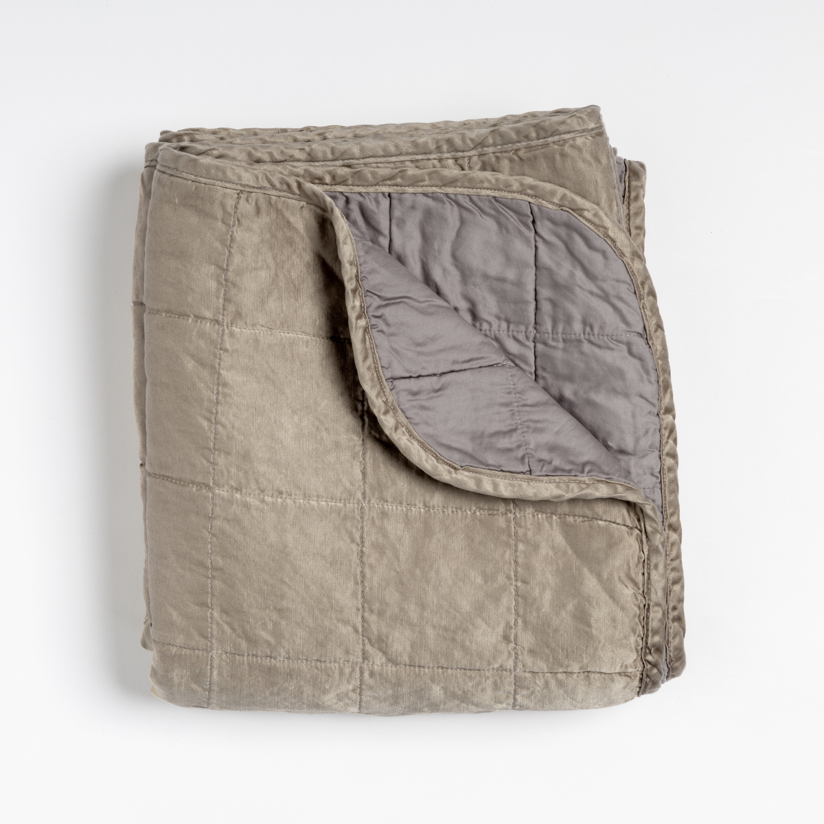 Moonlight: an overhead shot of a quilted charmeuse blanket in moonlight, a saturated, cool, mid-dark grey tone, with a corner folded down, showing its cotton sateen back. 