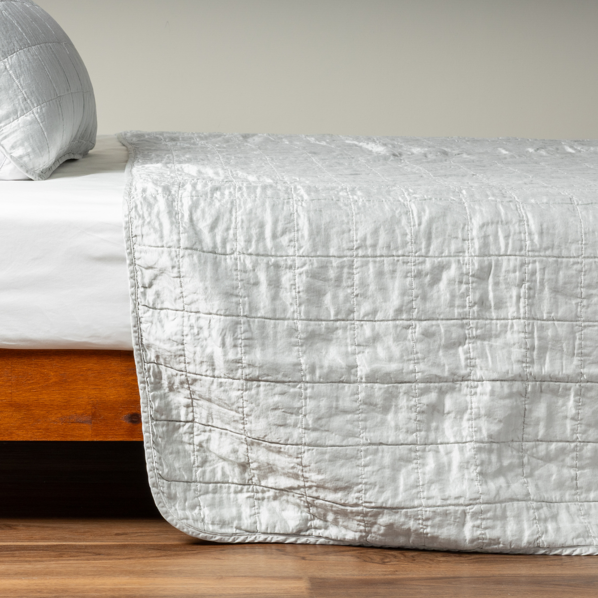 Cloud: A side shot of a square quilted charmeuse coverlet in cloud, a subtle sky blue-grey, with its matching sham.  