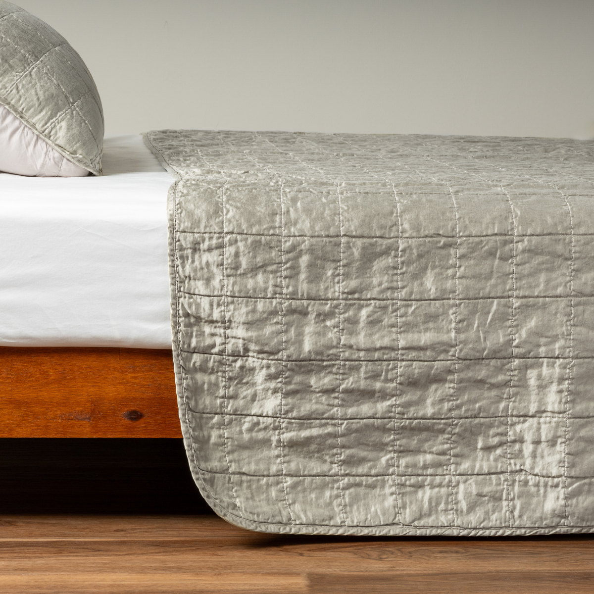 Fog: A side shot of a square quilted charmeuse coverlet in fog, a soft mid-tone grey, with its matching sham.  