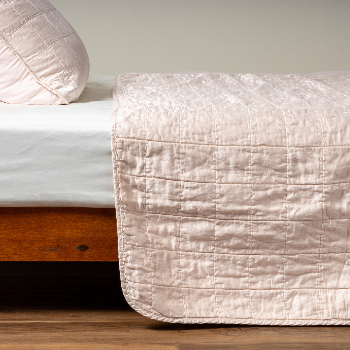 Pearl: A side shot of a square quilted charmeuse coverlet in pearl, a soft rose pink tone, with its matching sham.  
