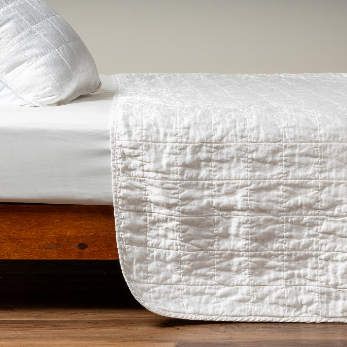White: A side shot of a square quilted charmeuse coverlet in classic white with its matching sham.  