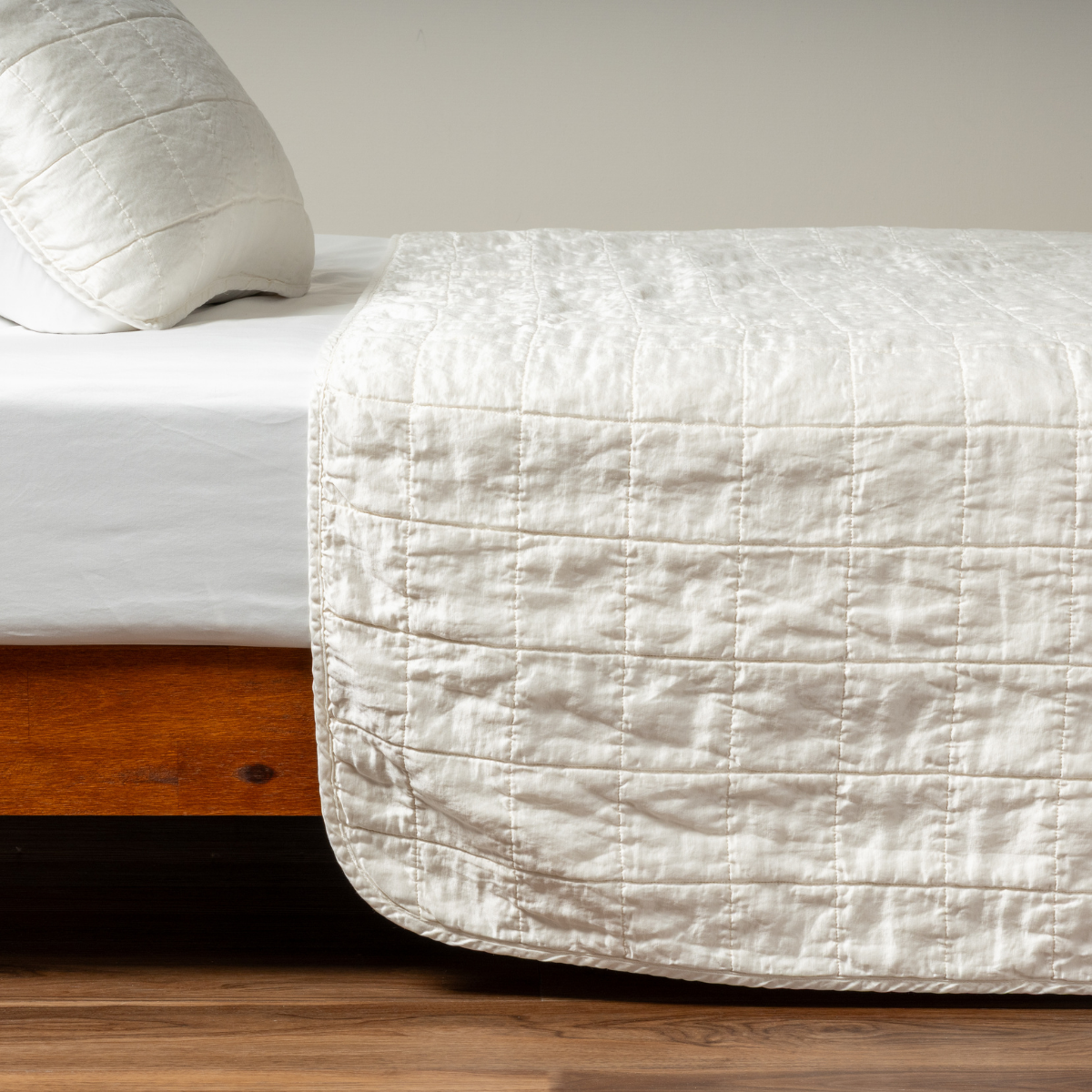 Winter White: A side shot of a square quilted charmeuse coverlet in winter white, a softer and warmer tone than our classic white, with its matching sham.  