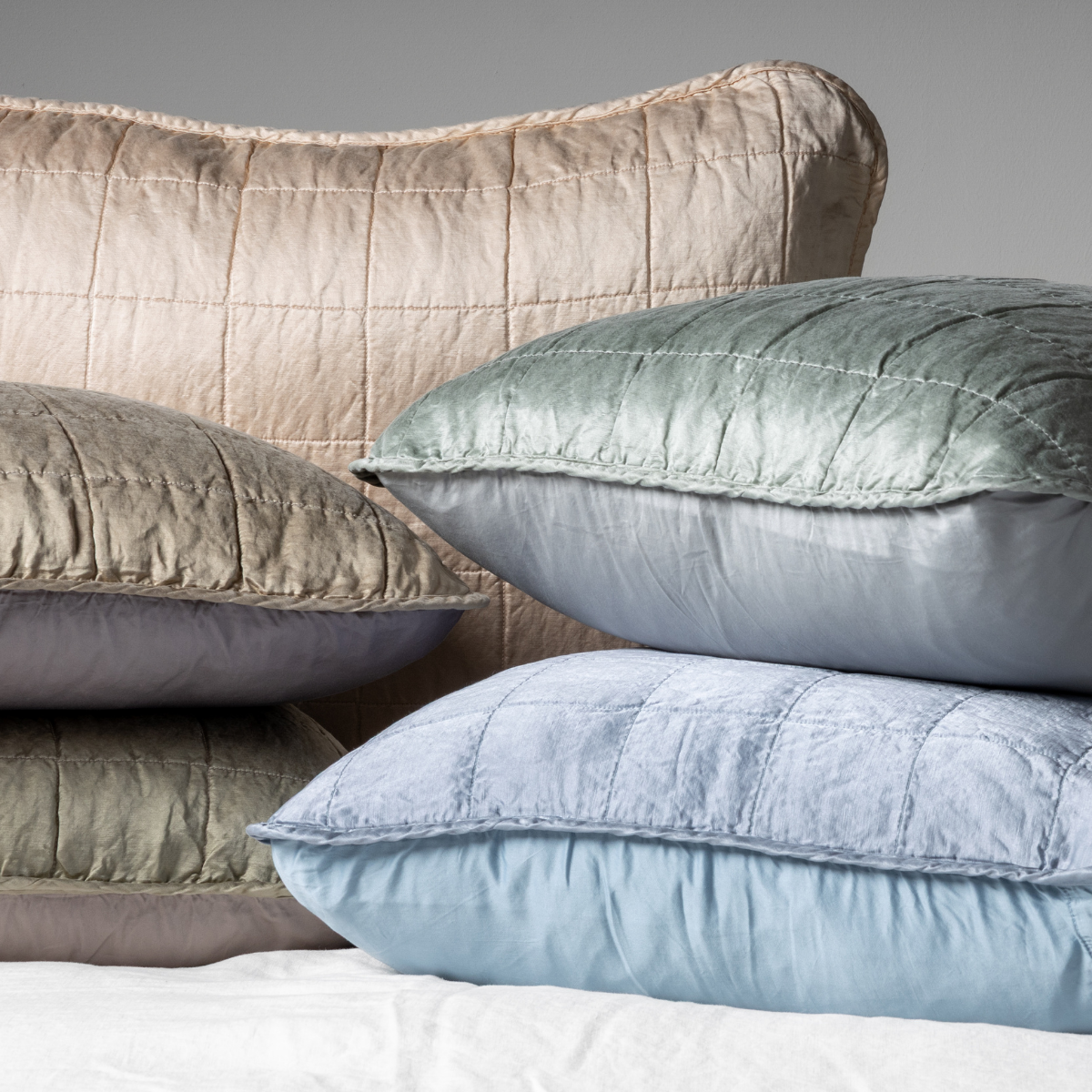 : A cluster shot of five charmeuse shams showing their square quilt patterned fronts and unquilted backs.  