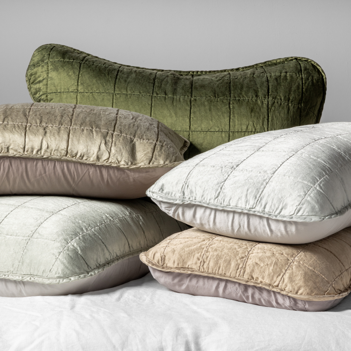 : A cluster shot of five square-quilted charmeuse shams showing their unquilted cotton sateen back. 