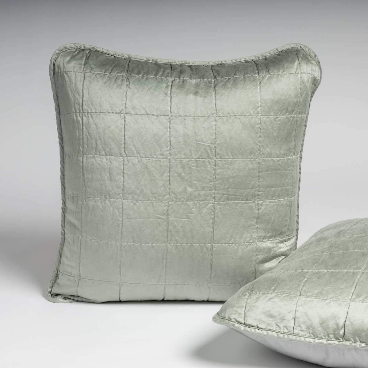 Mineral: A pair of shams shown in mineral, a soothing seafoam blue with subtle grey-green undertone, against a white background with one sham upright and the other on its side to show the cotton sateen back and square-quilted charmeuse front. 