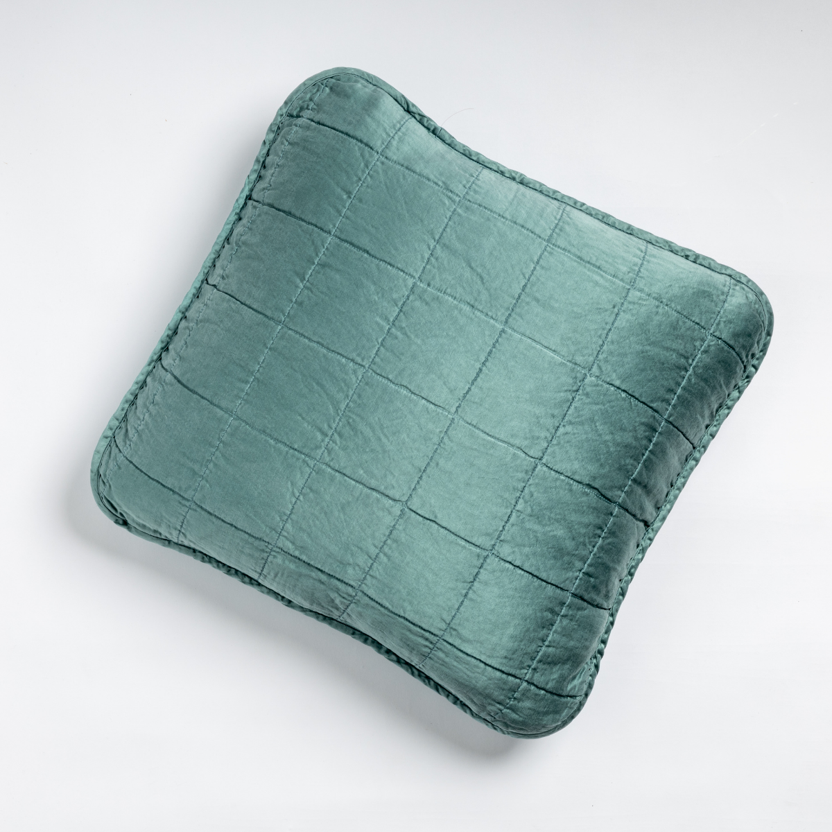 Cenote: An overhead shot of a square-quilted square throw pillow in cenote, a vibrant ocean-inspired blue-green, against a white background. 
