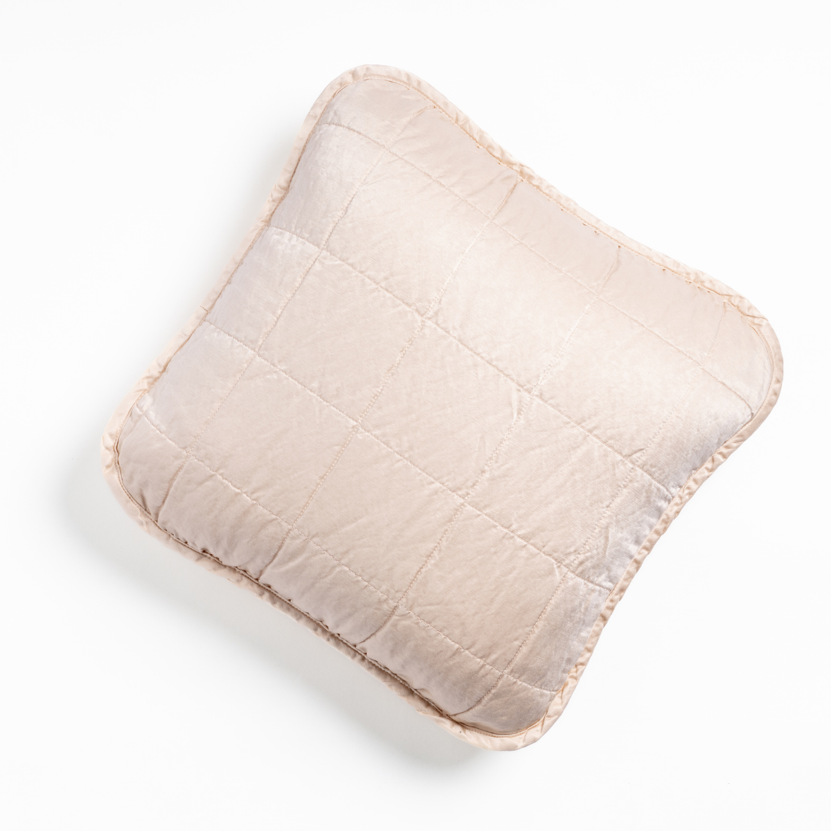 Pearl: An overhead shot of a square-quilted square throw pillow in pearl, a soft rose pink tone, against a white background. 