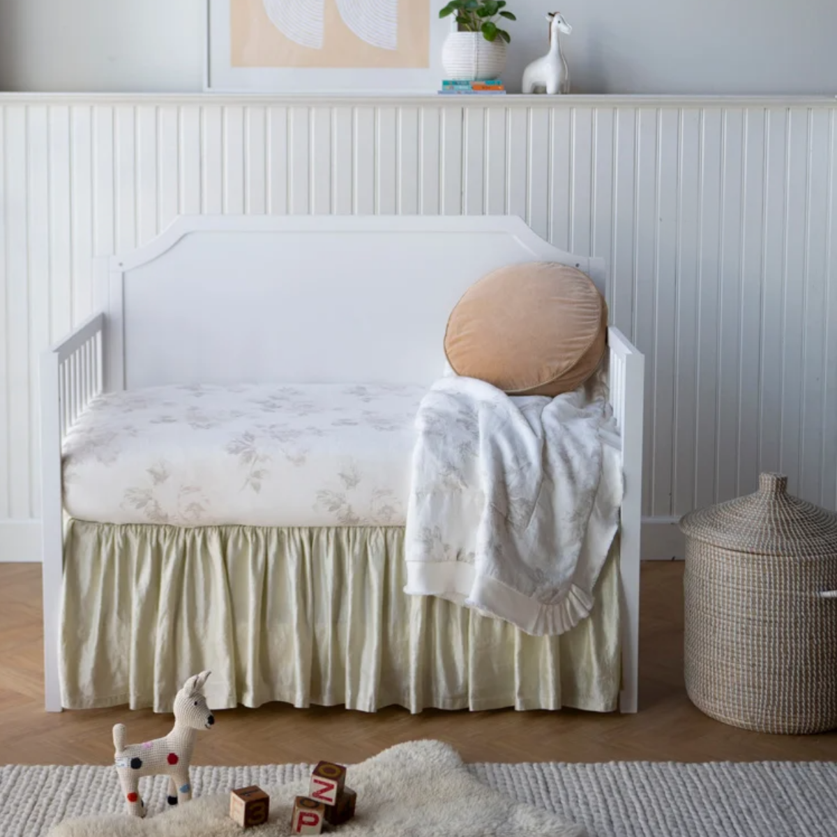 : Crib skirt in parchment in a nursery with soft white and neutral tones, highlighting the beautiful sheen of the charmeuse.