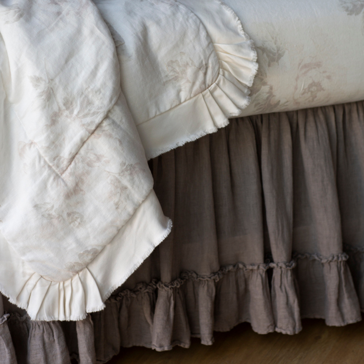 [allvariants]: Close up of crib skirt in moonlight under soft floral crib bedding showcases the gathering of the linen and the ruffle trim.