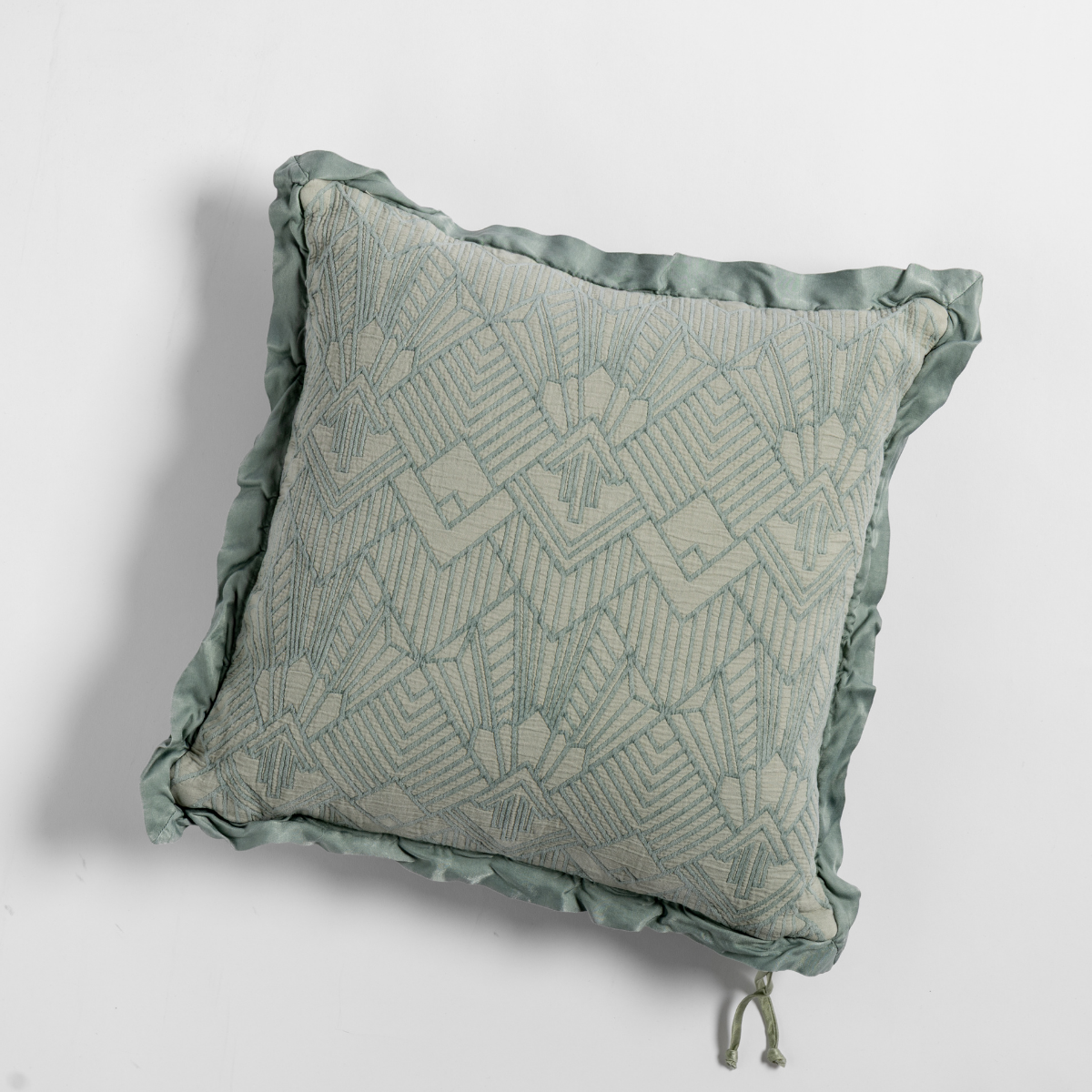 Eucalyptus: The cotton jacquard side of a textured throw pillow with contrasting ruffled edges, shot from overhead against a plain background.