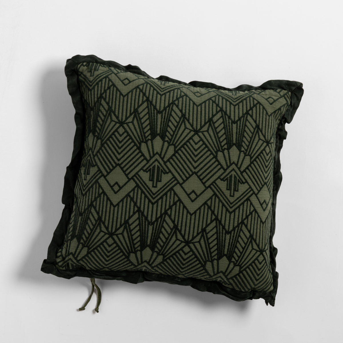 Juniper: The cotton jacquard side of a textured throw pillow with contrasting ruffled edges, shot from overhead against a plain background.