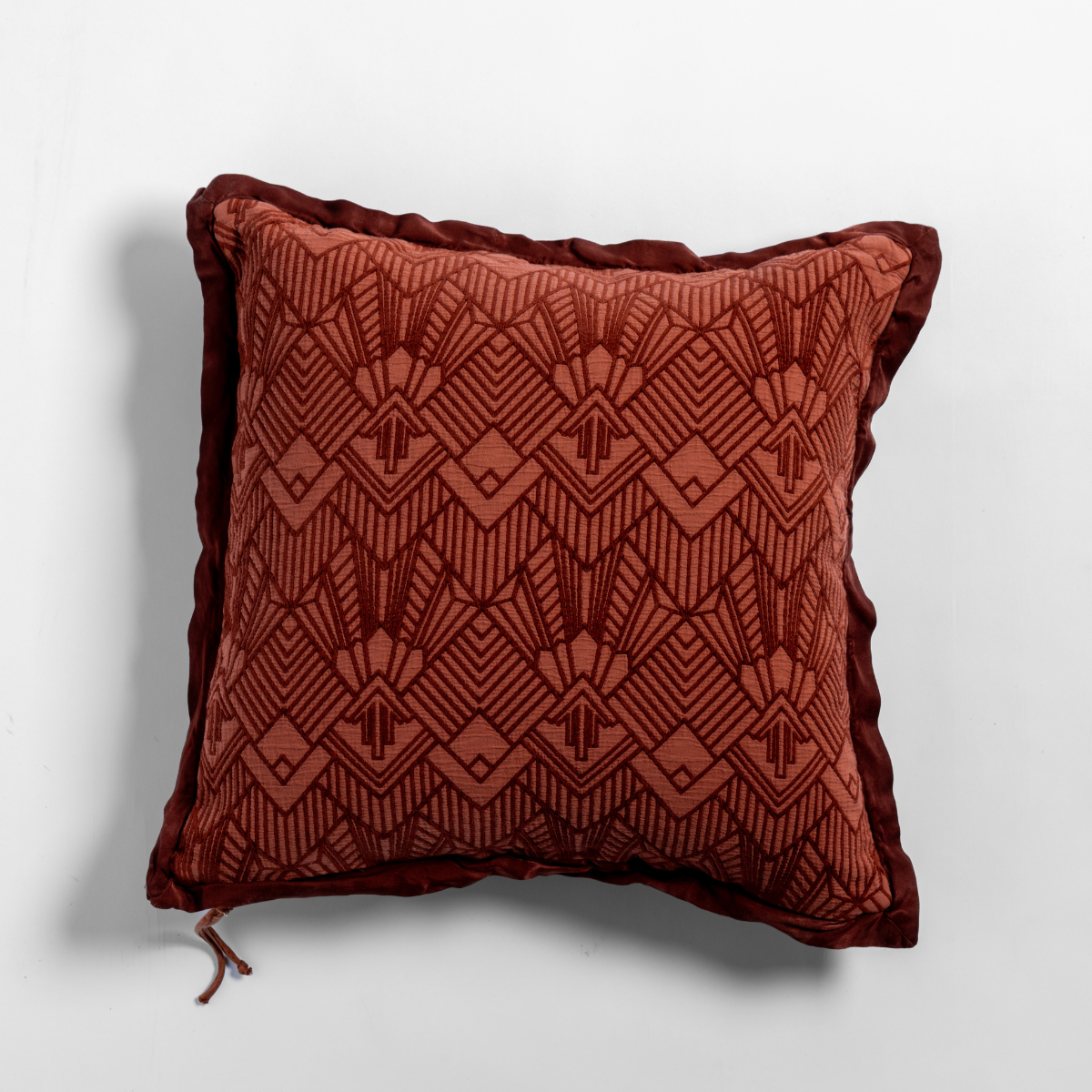 Autumn: The cotton jacquard side of a textured throw pillow with contrasting ruffled edges, shot from overhead against a plain background.