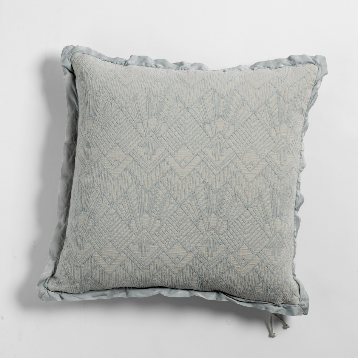 Cloud: The cotton jacquard side of a textured throw pillow with contrasting ruffled edges, shot from overhead against a plain background.