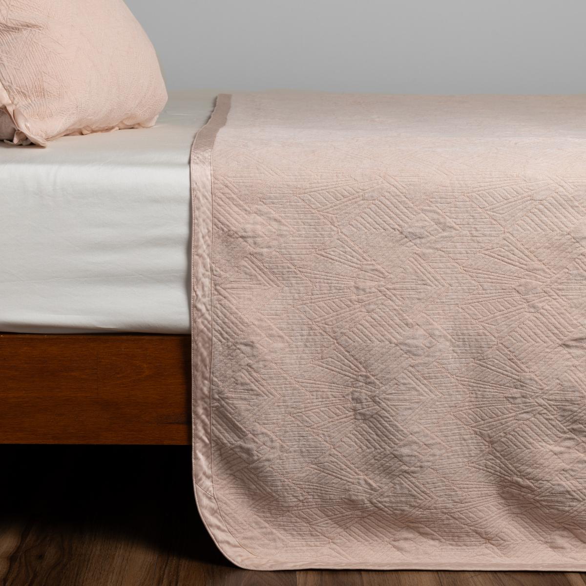 Pearl: textured bedspread on a bed with wooden bedframe.