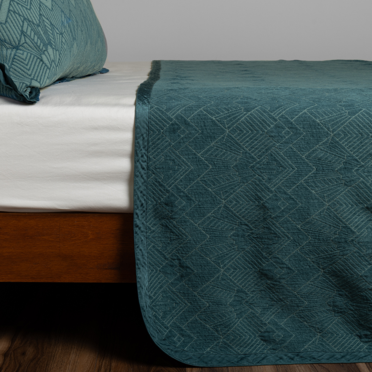 Cenote: textured bedspread on a bed with wooden bedframe.