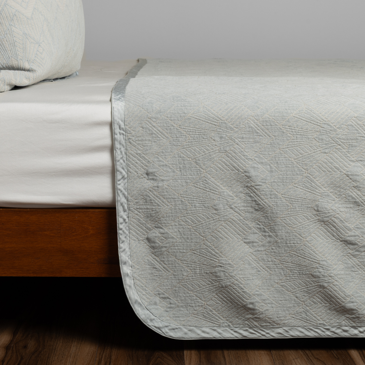 Cloud: textured bedspread on a bed with wooden bedframe.