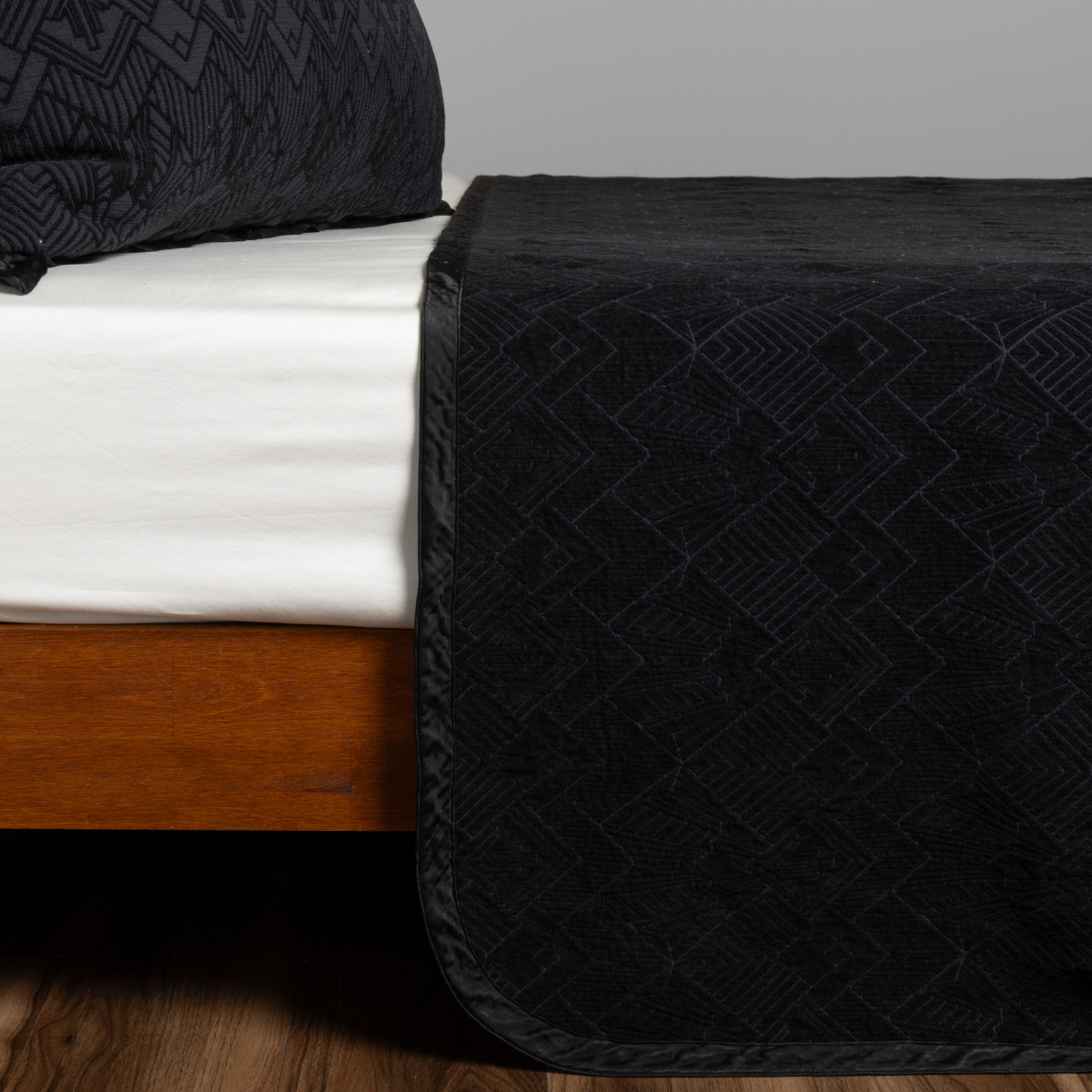 Corvino: textured bedspread on a bed with wooden bedframe.