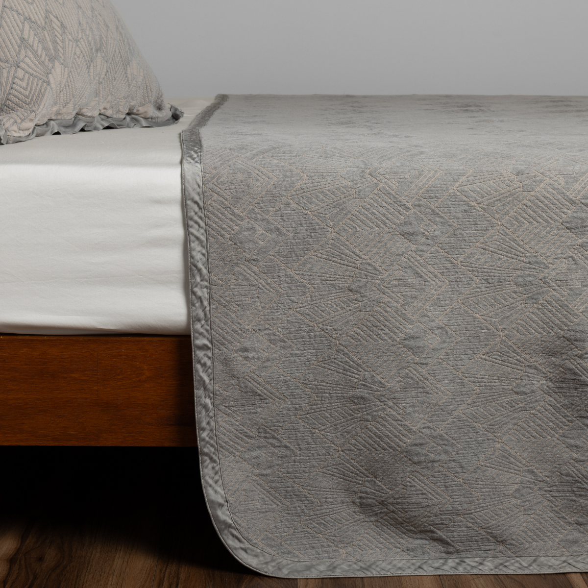 Fog: textured bedspread on a bed with wooden bedframe.