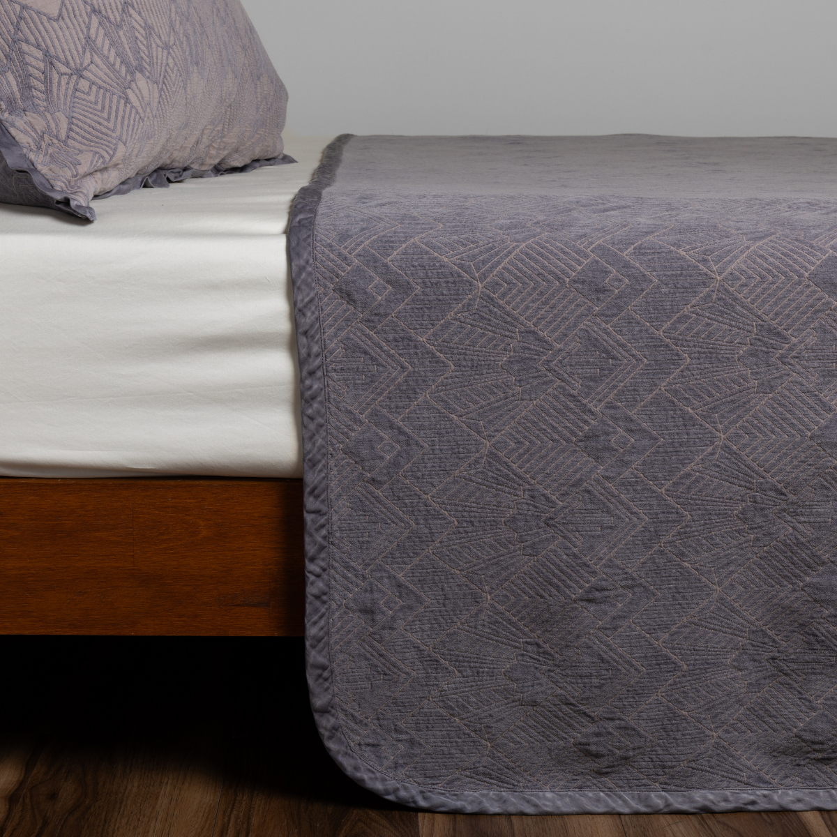 French Lavender: textured bedspread on a bed with wooden bedframe.