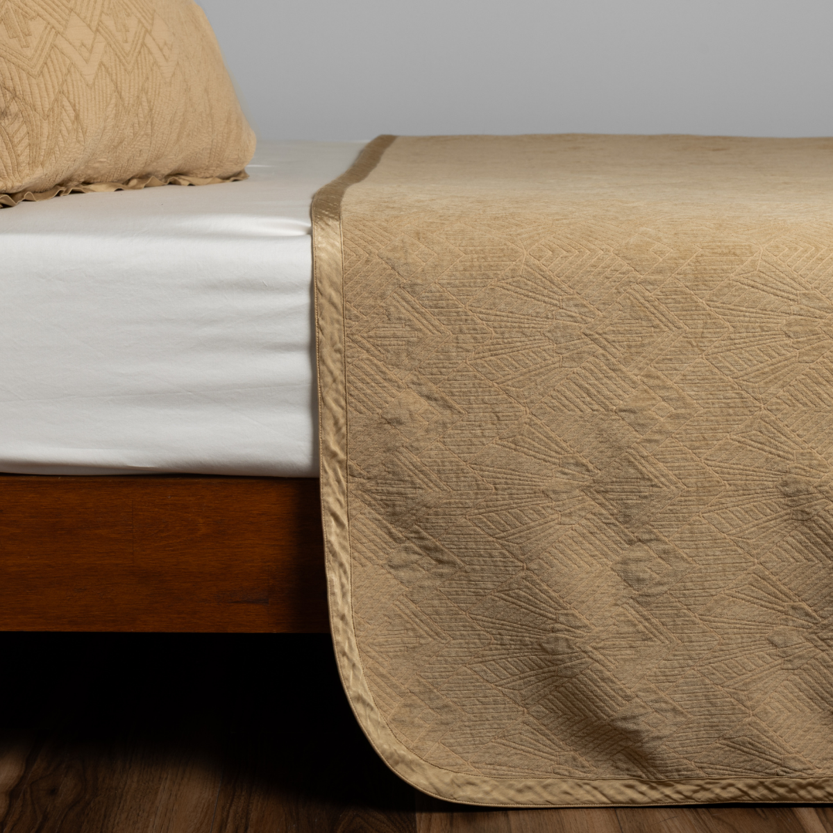 Honeycomb: textured bedspread on a bed with wooden bedframe.