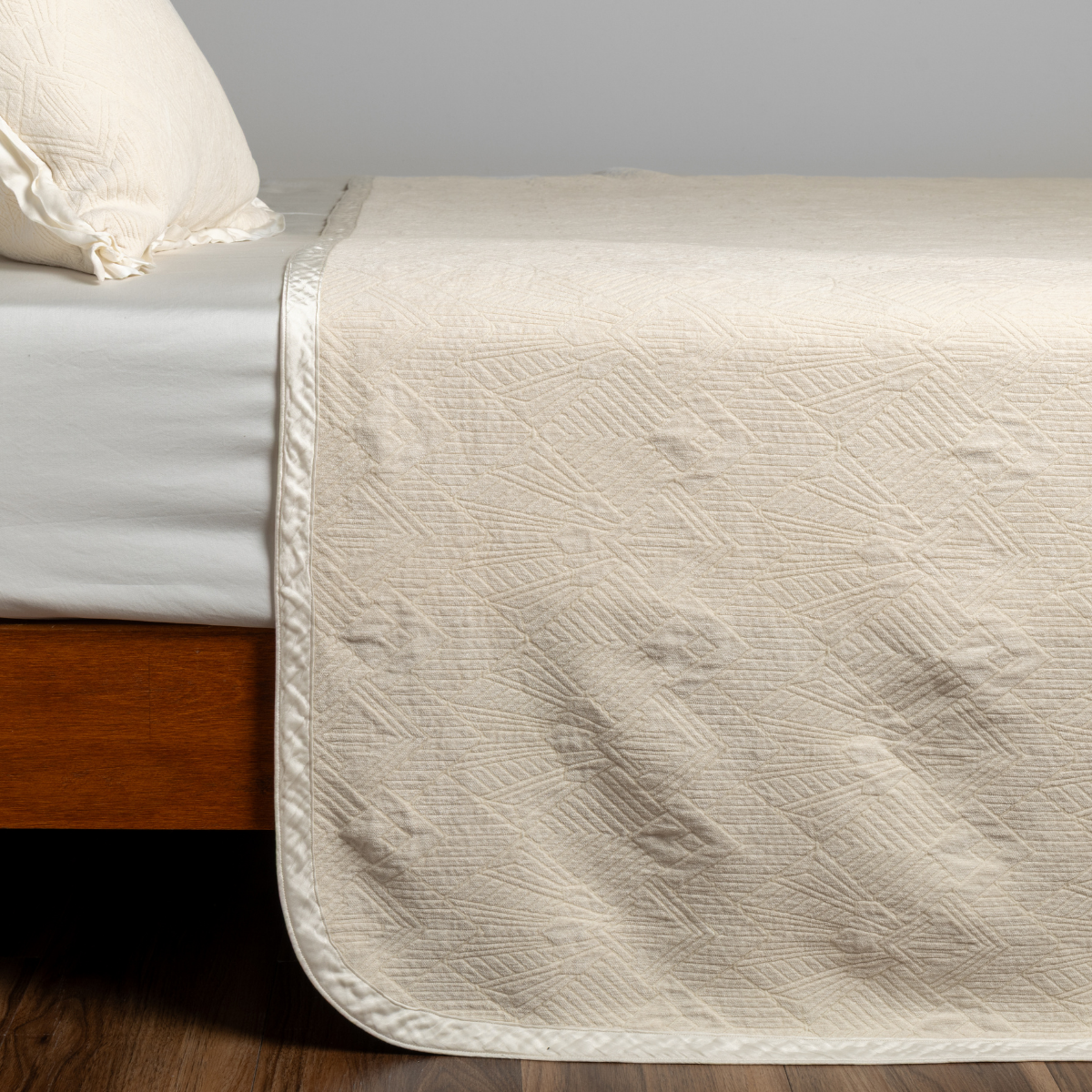 Natural: textured bedspread on a bed with wooden bedframe.