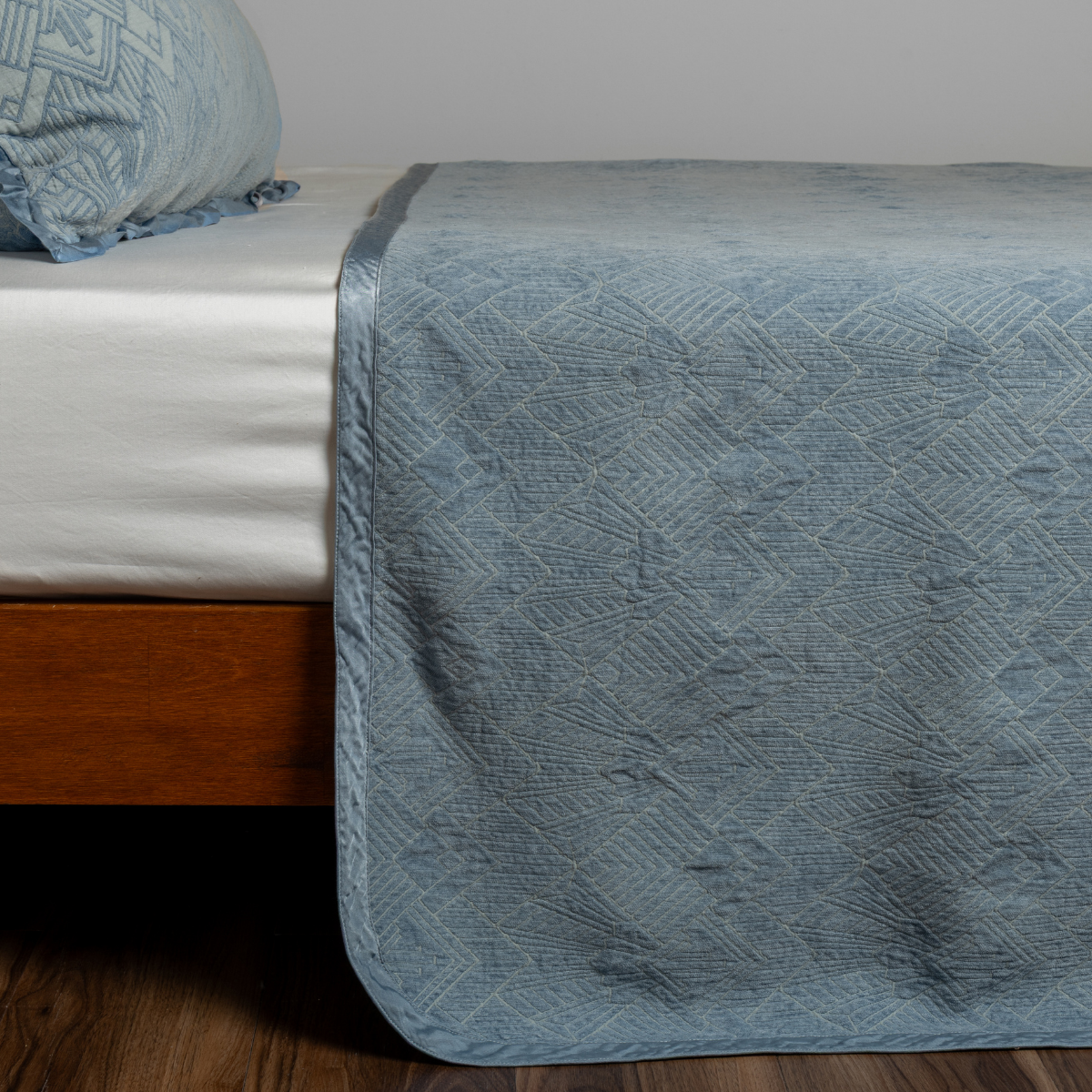 Tahoe Blue: textured bedspread on a bed with wooden bedframe.