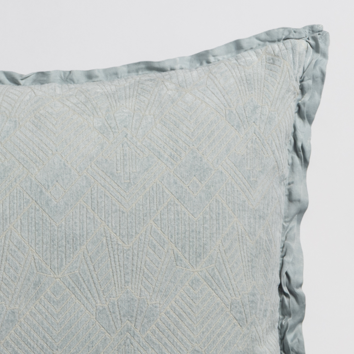 Cloud: Close-up of a textured pillow sham corner with a satin ruffle, shot against a plain background.