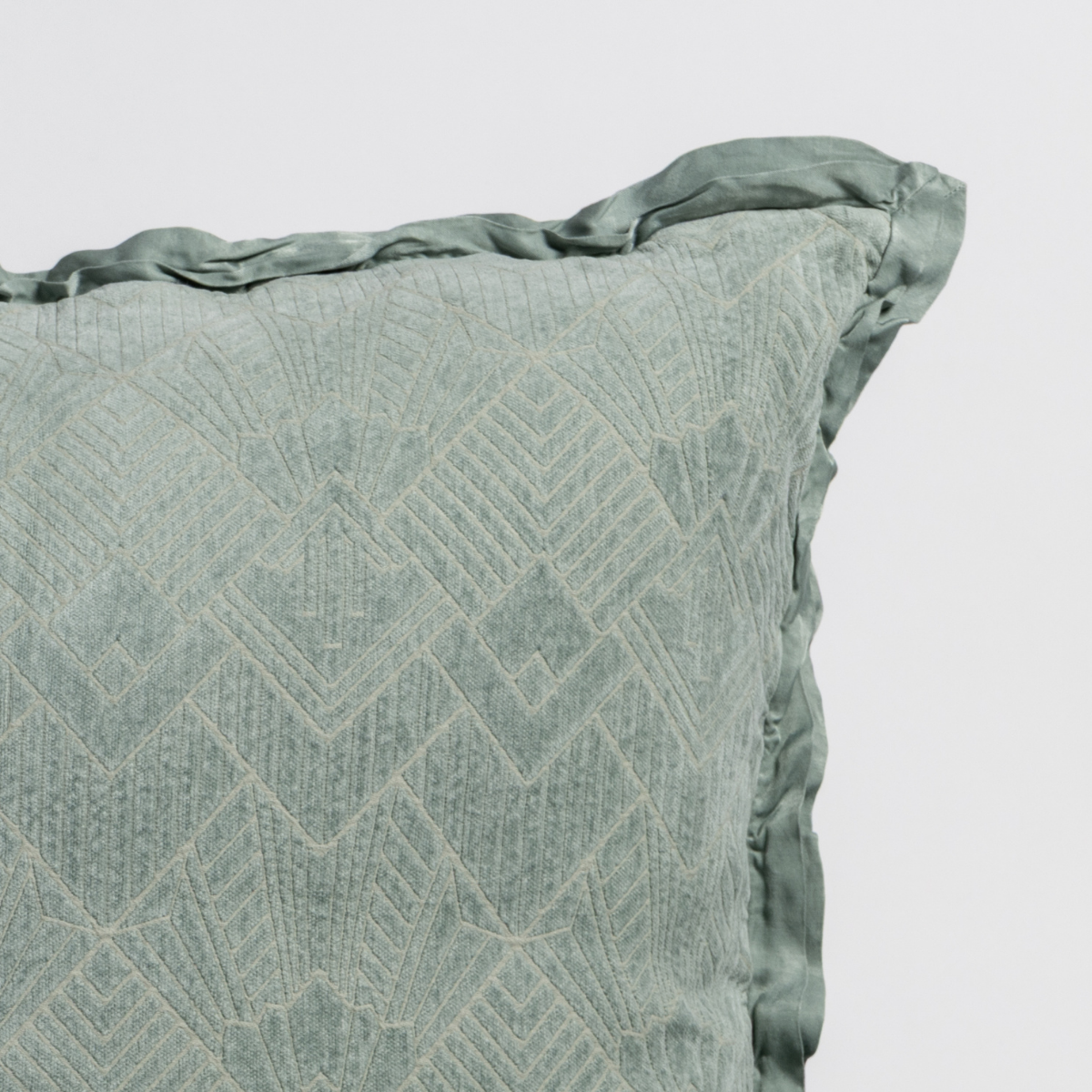Eucalyptus: Close-up of a textured pillow sham corner with a satin ruffle, shot against a plain background.