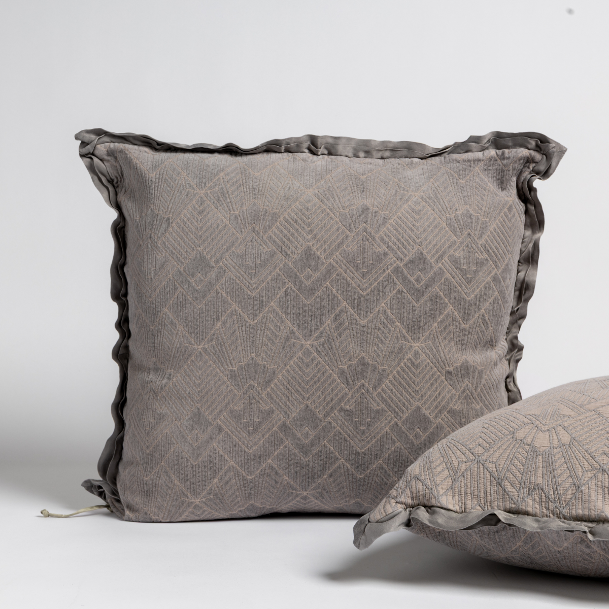 Fog: Two art deco patterned shams, one upright and one on its side, against a plain background.