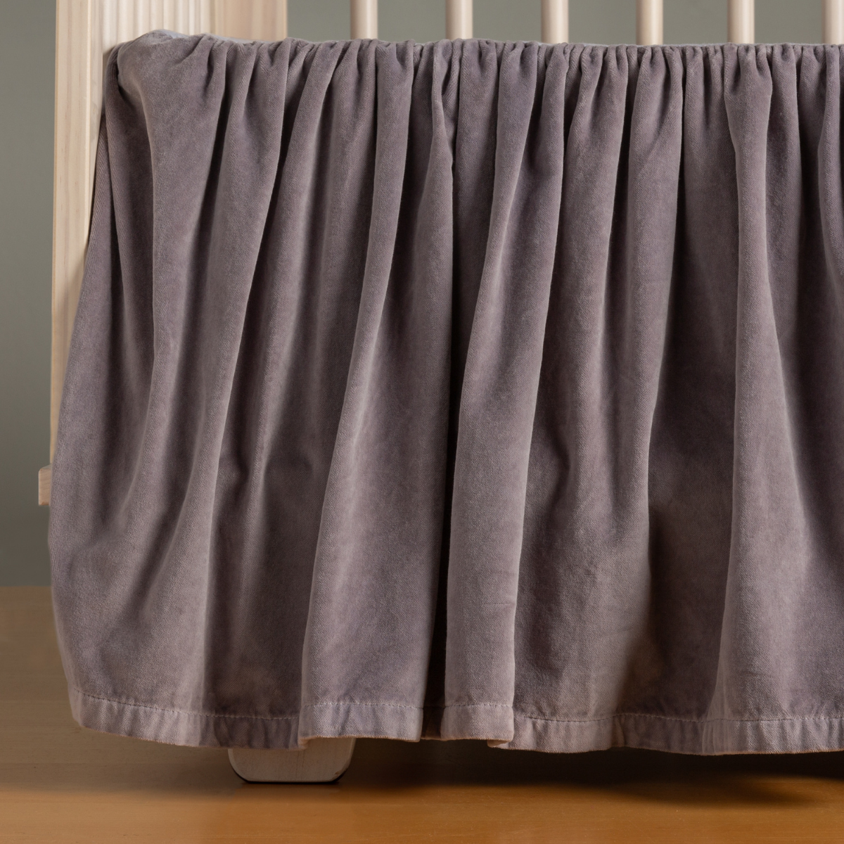 French Lavender: coton velvet crib skirt shown on a light wood crib. 