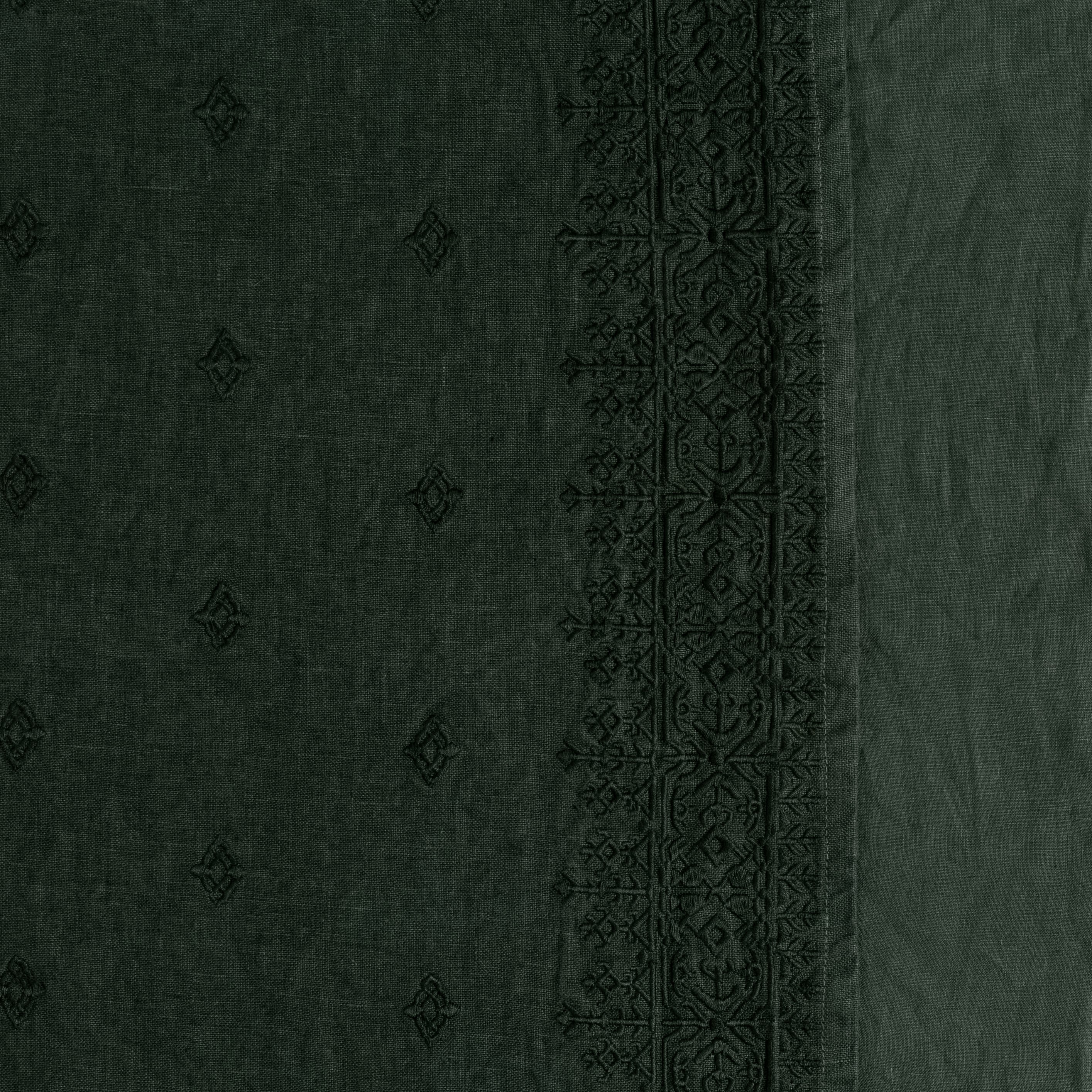 A close up of embroidered midweight linen in juniper, a dark green tone. 