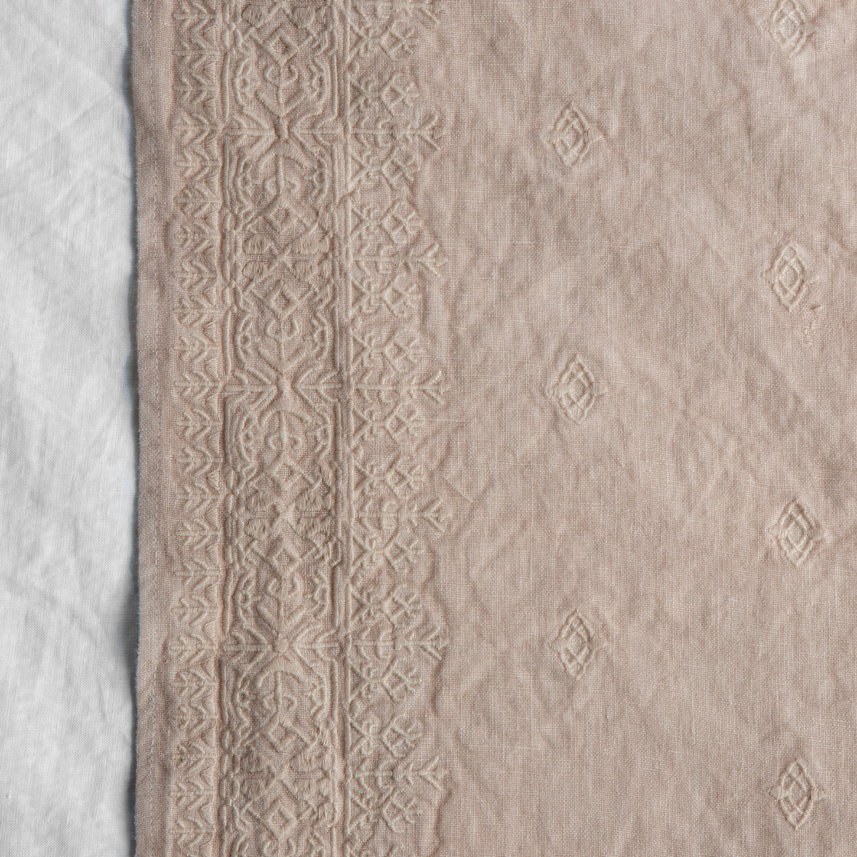 Pearl: A close up of Ines, midweight linen with cotton embroidery, in pearl, a nude-like, soft rose pink tone. 
