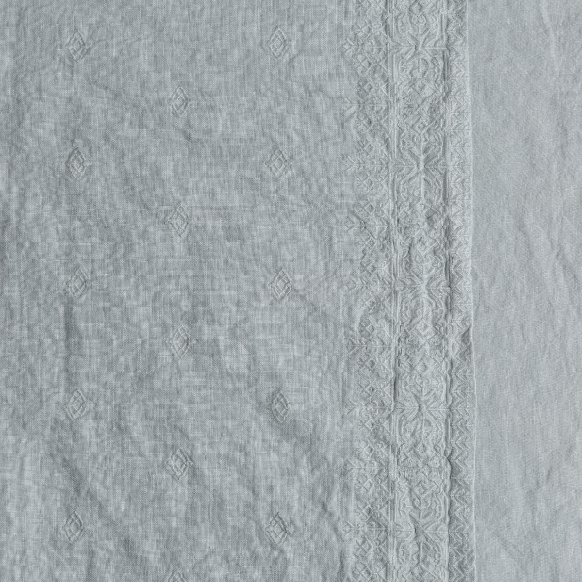 Cloud: A close up of embroidered midweight linen fabric in cloud, a soft, subtle sky blue-grey.