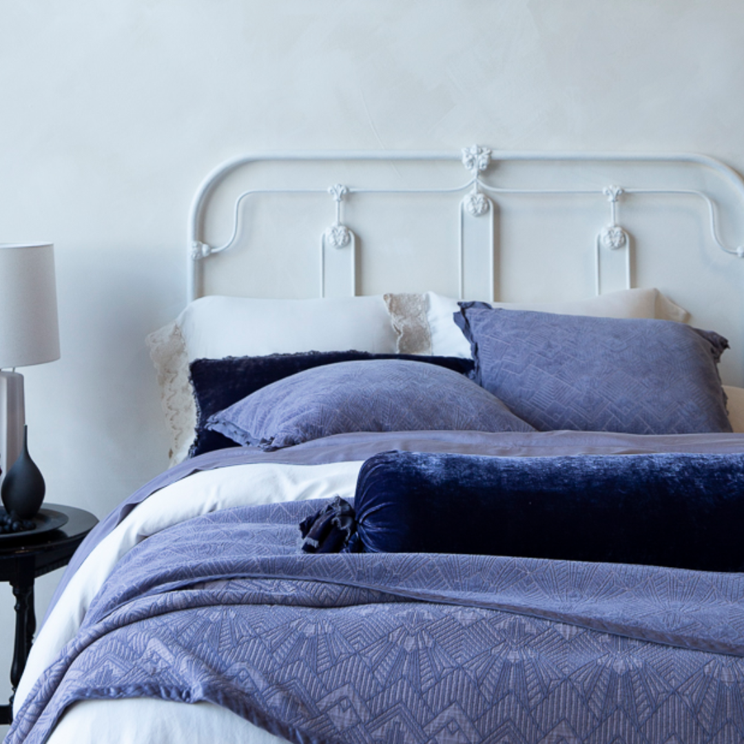 [allvariants]: Bed with purple bedding and pillows in a bedroom setting