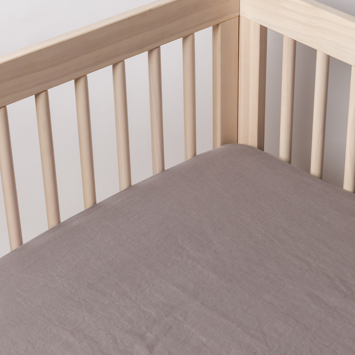 French Lavender: linen crib sheet shown on a mattress shot into the inside corner of the crib. 