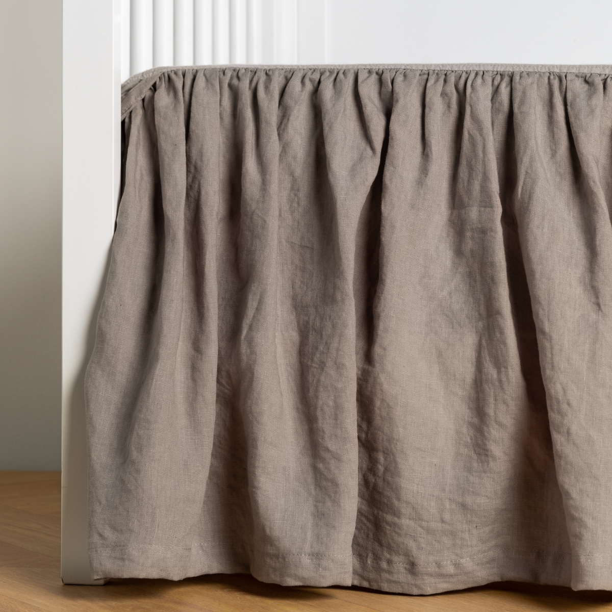 Moonlight:  crib skirt shown on a white crib with no mattress against a white wall and medium wood flooring. 