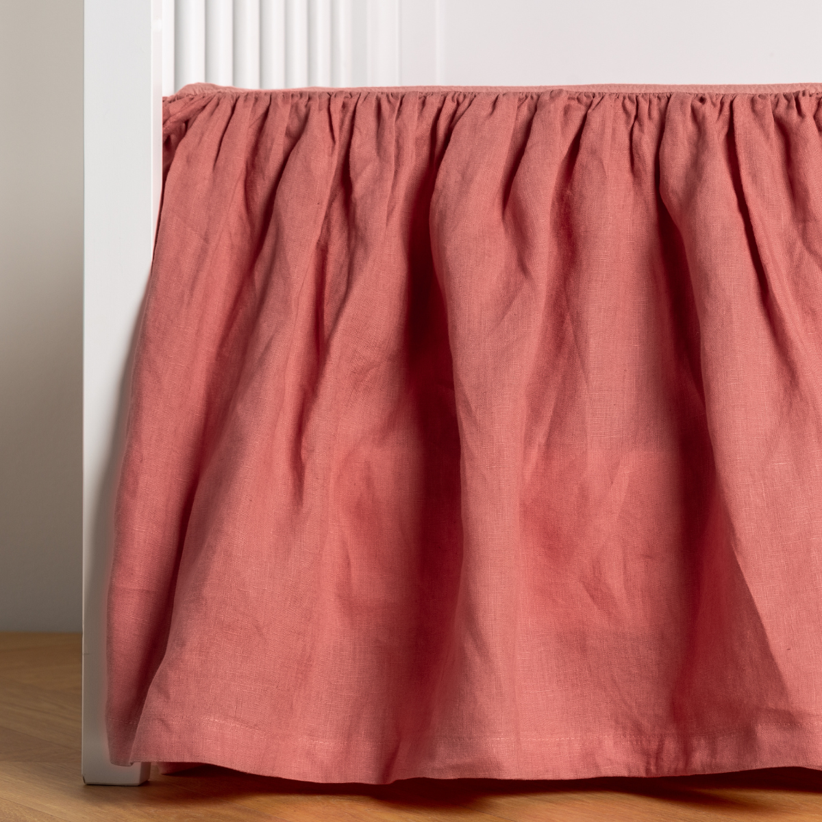 Poppy:  crib skirt shown on a white crib with no mattress against a white wall and medium wood flooring. 