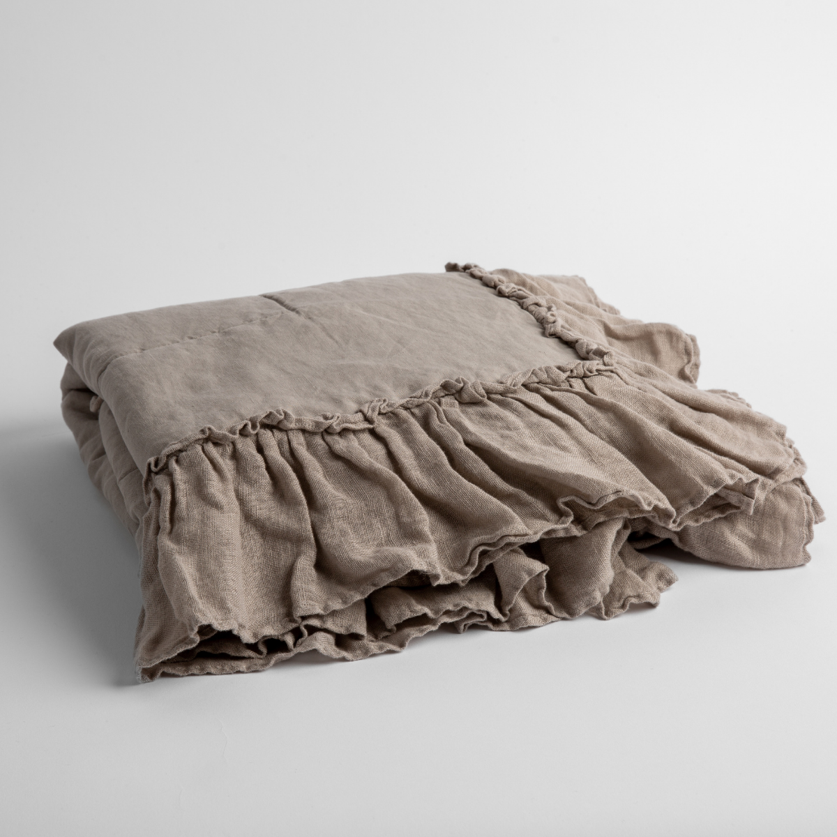 Fog:   a folded linen with linen whisper ruffled blanket folded and positioned to show the ruffle detail against a white background and slightly overhead. 