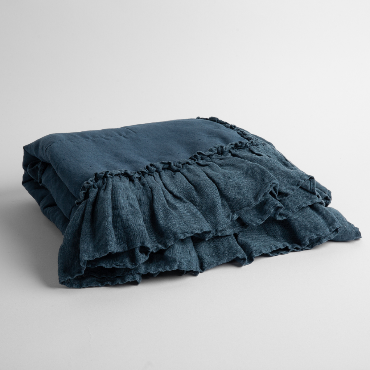 Midnight:   a folded linen with linen whisper ruffled blanket folded and positioned to show the ruffle detail against a white background and slightly overhead. 