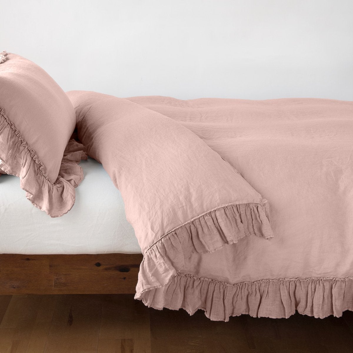 Rouge: duvet cover folded back over a white fitted sheet, shown with matching sham against a plain background - side view.