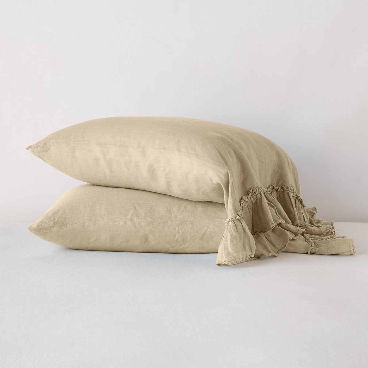 Honeycomb: Two sleeping pillows stacked at a slight angle against a plain background, showcasing ruffle trim detail - side view.