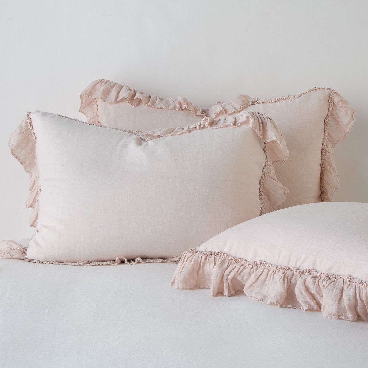 Pearl: two shams leaning upright and one laying flat at an angle in the foreground, against a blank background.