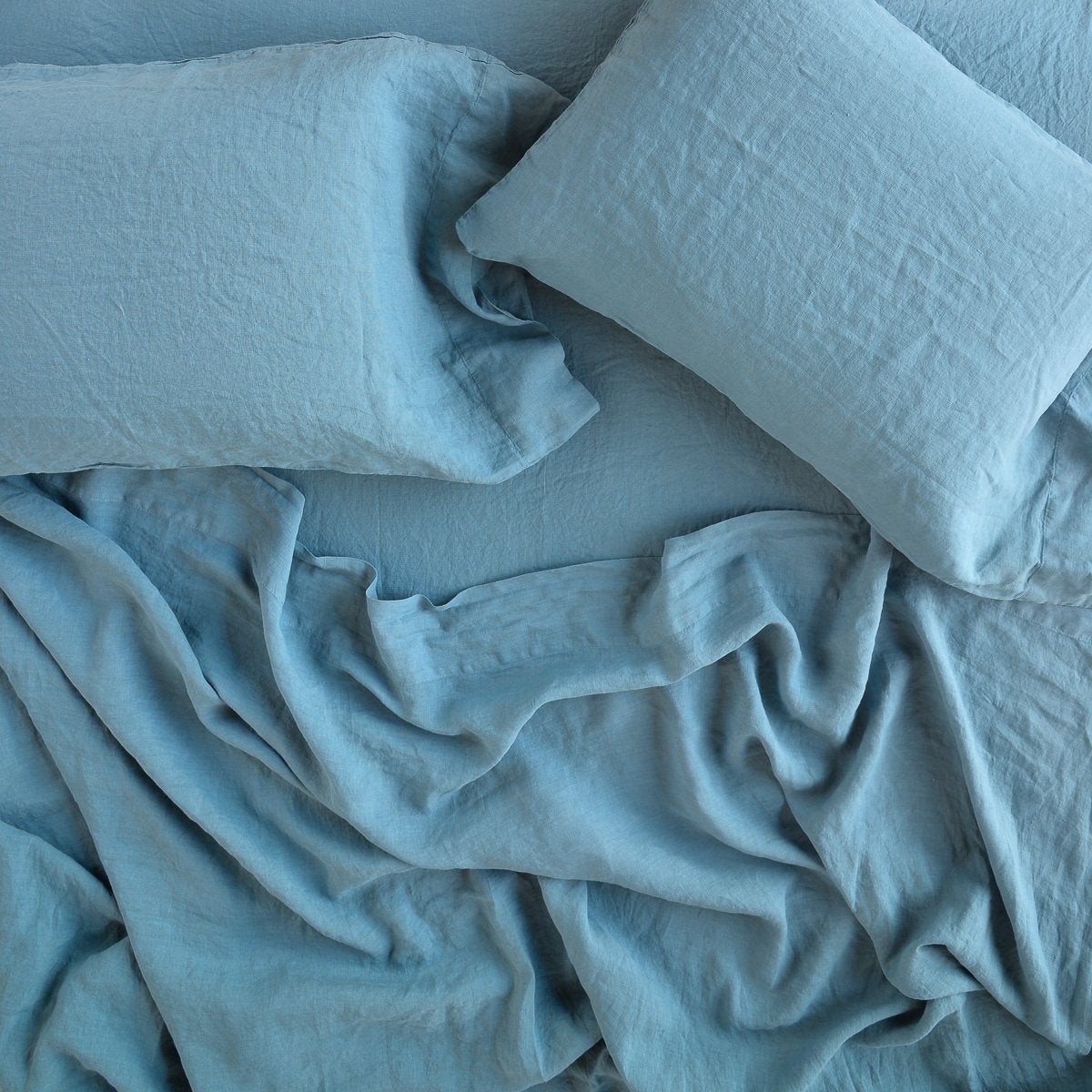 Cenote: sleeping pillows laid flat on rumpled matching sheeting - overhead view.